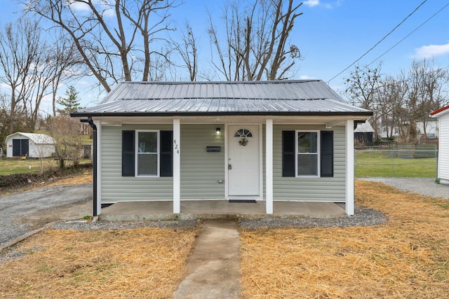 bungalow-style house featuring metal roof, a porch, a front yard, and fence