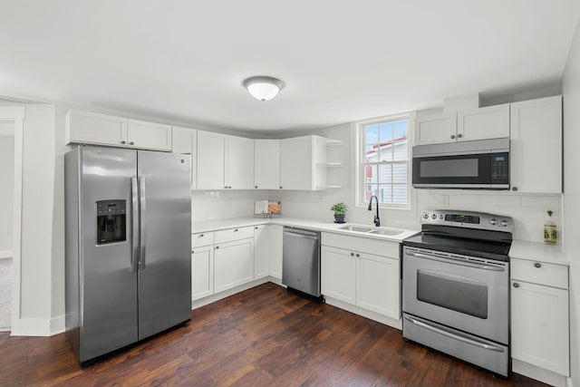 kitchen featuring dark wood finished floors, stainless steel appliances, light countertops, decorative backsplash, and a sink