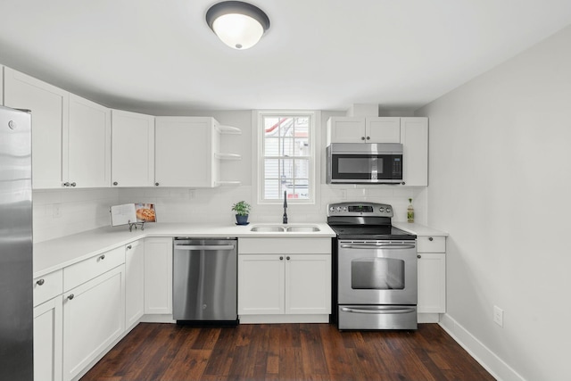 kitchen with a sink, stainless steel appliances, white cabinetry, open shelves, and backsplash