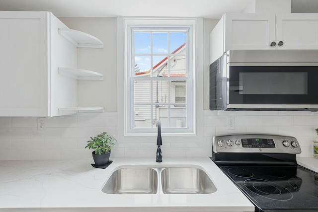 kitchen with white cabinets, decorative backsplash, stainless steel appliances, open shelves, and a sink