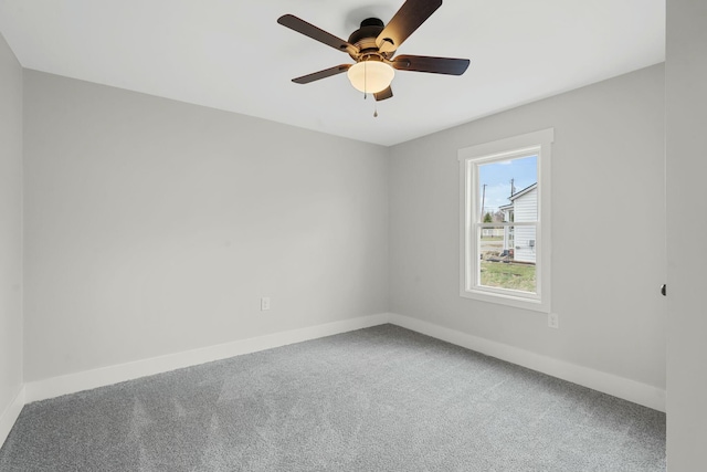 carpeted spare room with a ceiling fan and baseboards