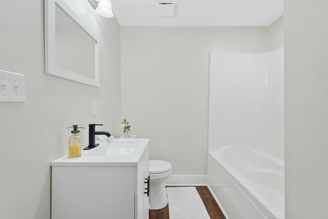 bathroom with baseboards, toilet, wood finished floors, vanity, and shower / washtub combination