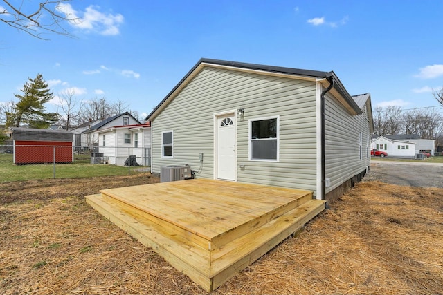 back of house with central AC unit, fence, a deck, and a yard