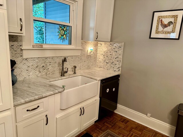 kitchen with baseboards, light stone counters, a sink, white cabinetry, and backsplash