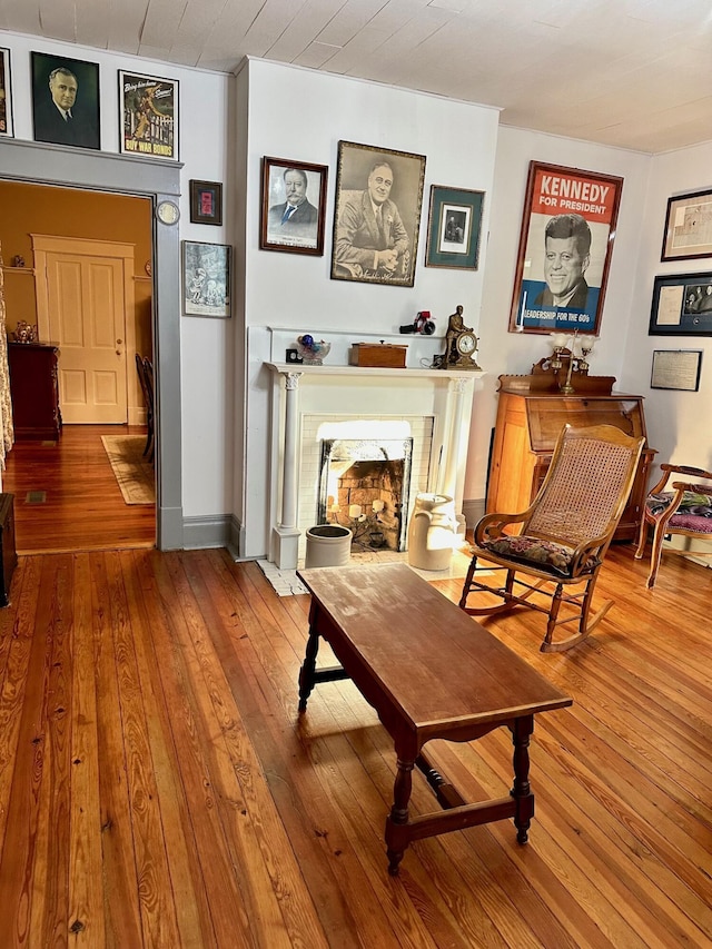 sitting room with a fireplace with flush hearth, baseboards, and wood finished floors