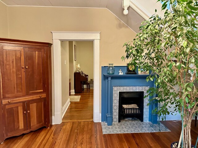 interior space with lofted ceiling, a tile fireplace, and wood finished floors