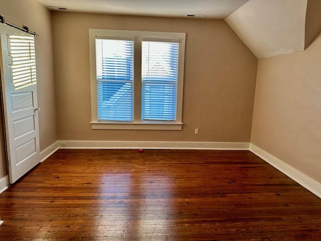 additional living space with lofted ceiling, visible vents, baseboards, and dark wood-style flooring