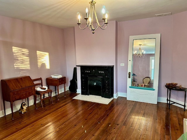 sitting room with dark wood-type flooring, a fireplace with flush hearth, visible vents, baseboards, and an inviting chandelier