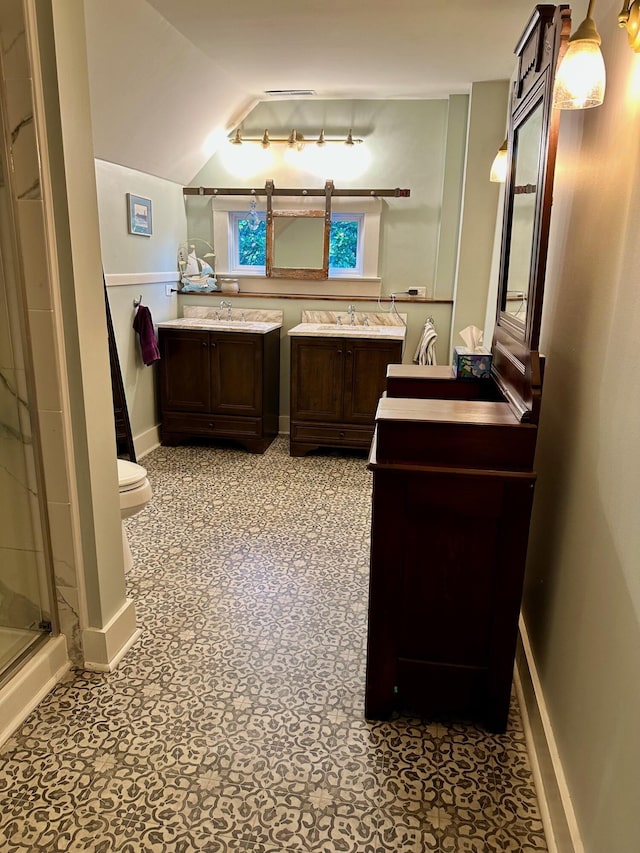 bathroom featuring a stall shower, toilet, a sink, vaulted ceiling, and two vanities