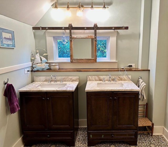 bathroom with vaulted ceiling, two vanities, a sink, and baseboards