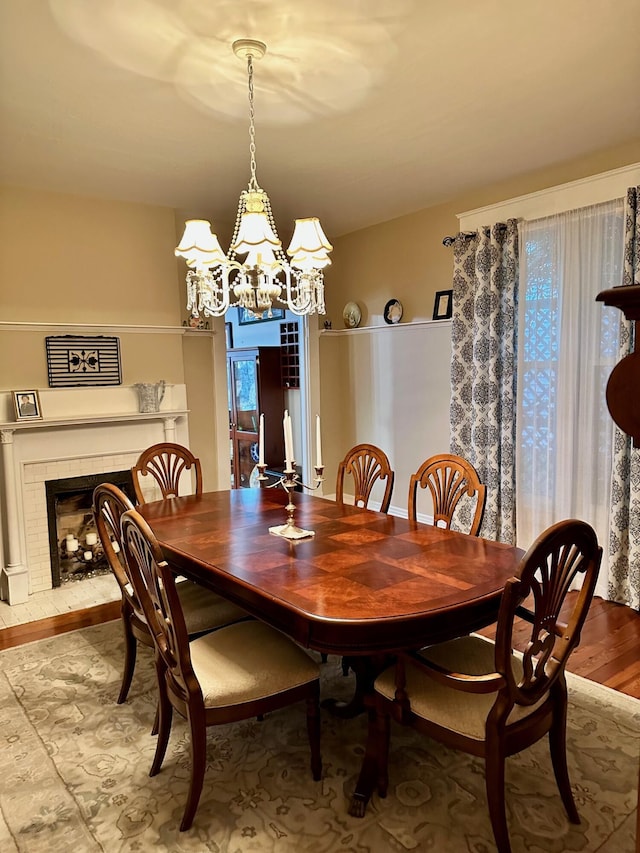 dining space featuring an inviting chandelier and a fireplace with raised hearth