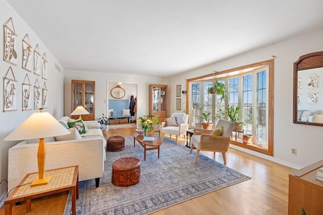 living area with visible vents, baseboards, and wood finished floors