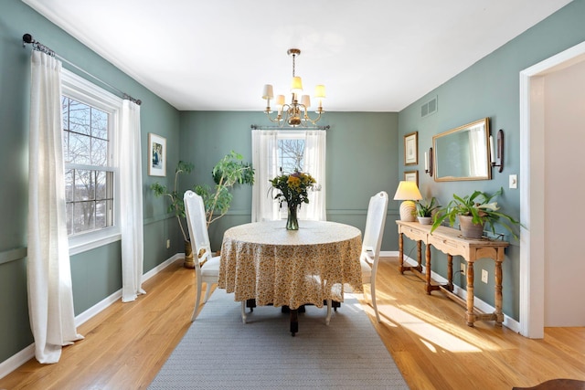 dining room featuring a chandelier, visible vents, light wood-style flooring, and baseboards