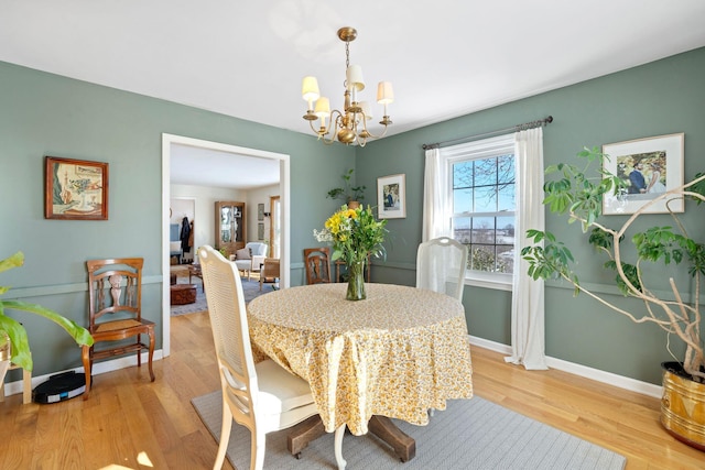 dining room with baseboards, light wood-style floors, and an inviting chandelier