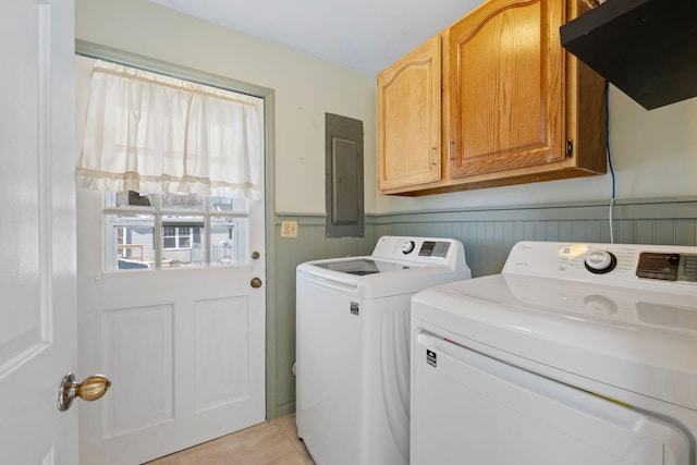 laundry area with light tile patterned flooring, washing machine and dryer, wainscoting, cabinet space, and electric panel