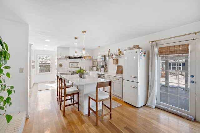 kitchen featuring light wood-style floors, freestanding refrigerator, light countertops, and open shelves