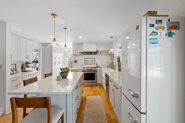 kitchen featuring stainless steel appliances, a kitchen island, white cabinets, light countertops, and light wood-type flooring