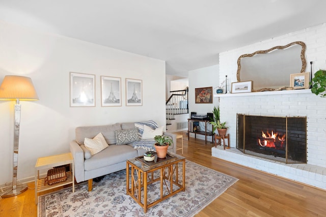 living area with stairs, a fireplace, wood finished floors, and baseboards