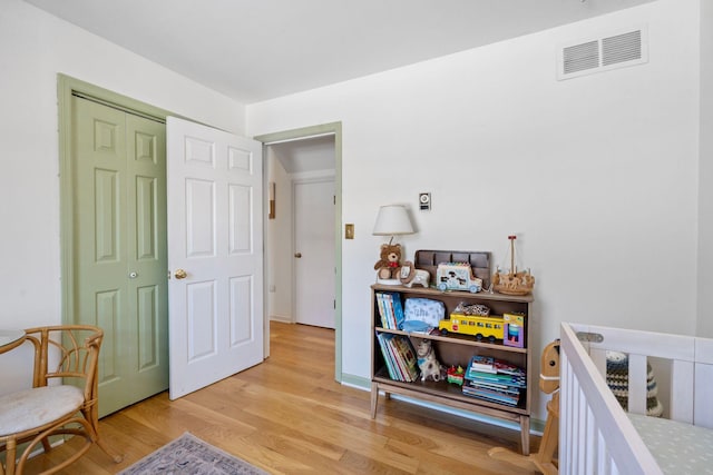 bedroom with light wood finished floors, baseboards, visible vents, and a closet