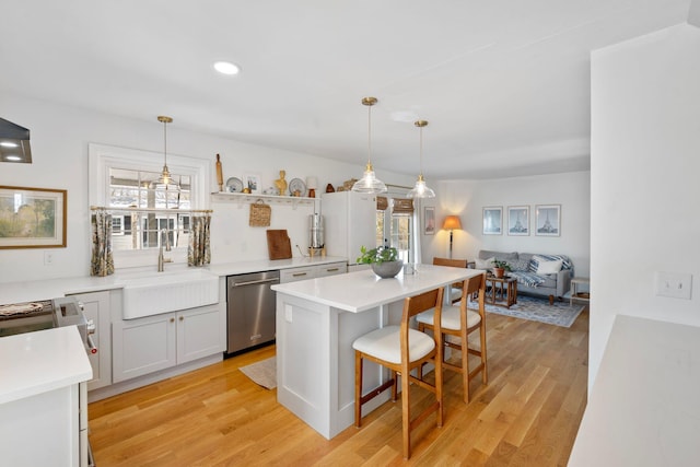 kitchen featuring a breakfast bar area, light wood finished floors, open shelves, a sink, and dishwasher