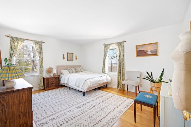 bedroom with light wood finished floors, multiple windows, and baseboards