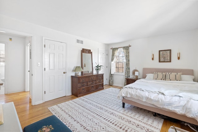 bedroom with light wood-style flooring, visible vents, and baseboards