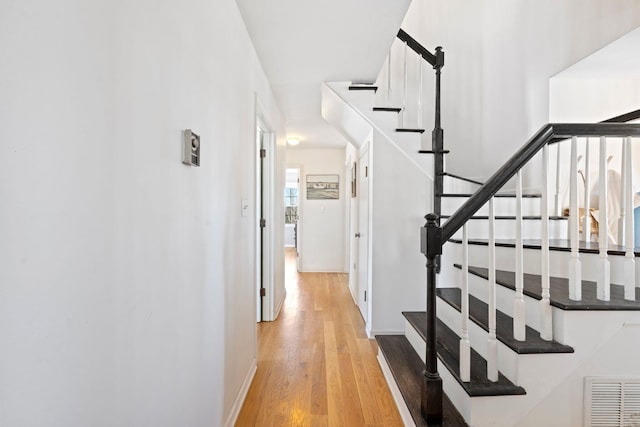 stairway with wood finished floors, visible vents, and baseboards