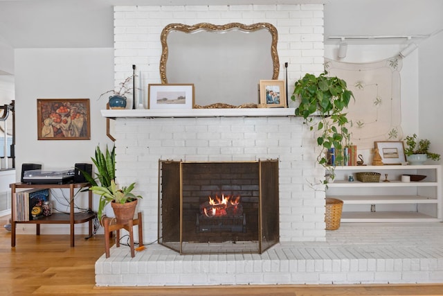 interior space with a brick fireplace and wood finished floors