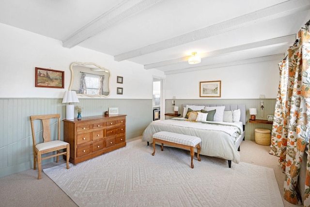 bedroom with a wainscoted wall, carpet flooring, and beam ceiling