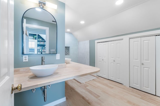 full bathroom featuring lofted ceiling, a sink, recessed lighting, and wood finished floors