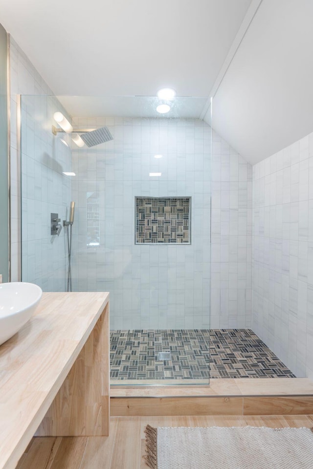 bathroom featuring lofted ceiling, a tile shower, vanity, and wood finished floors