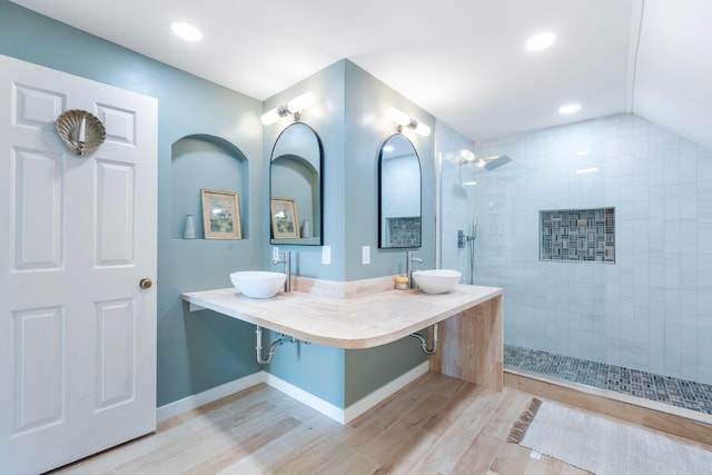 bathroom featuring a walk in shower, a sink, baseboards, and wood finished floors