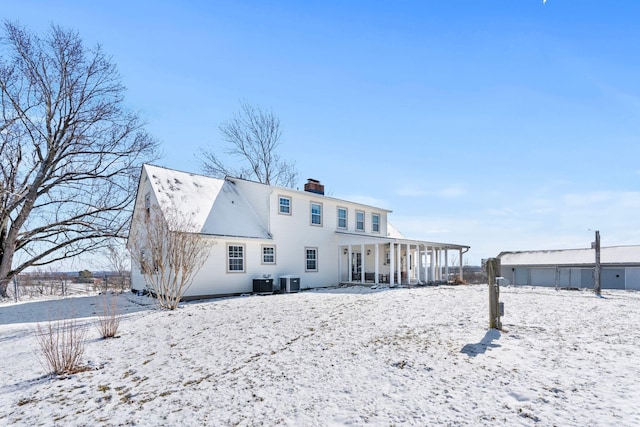 snow covered rear of property with a chimney and central air condition unit