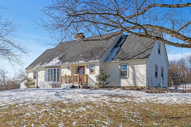 colonial inspired home with a shingled roof, a chimney, and fence