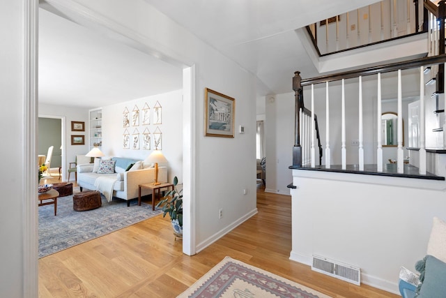 interior space featuring light wood finished floors, baseboards, stairway, and visible vents