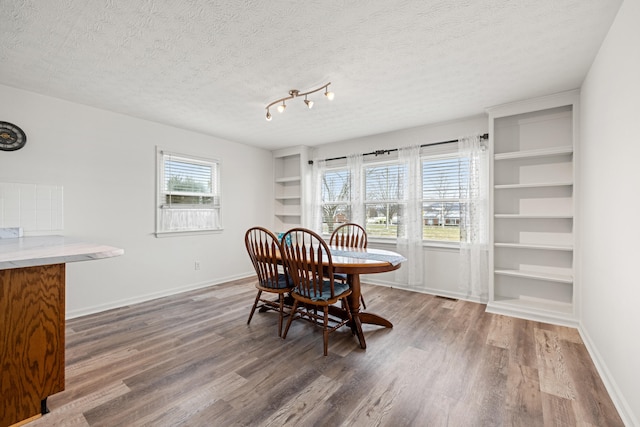 dining area with a healthy amount of sunlight, a textured ceiling, and dark hardwood / wood-style flooring