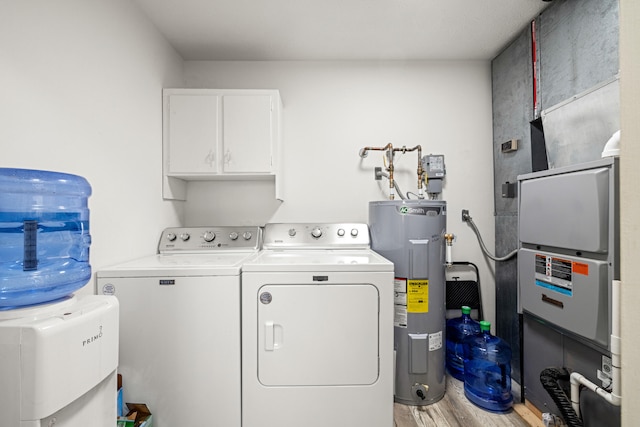 washroom with cabinets, hardwood / wood-style flooring, electric water heater, and washing machine and clothes dryer