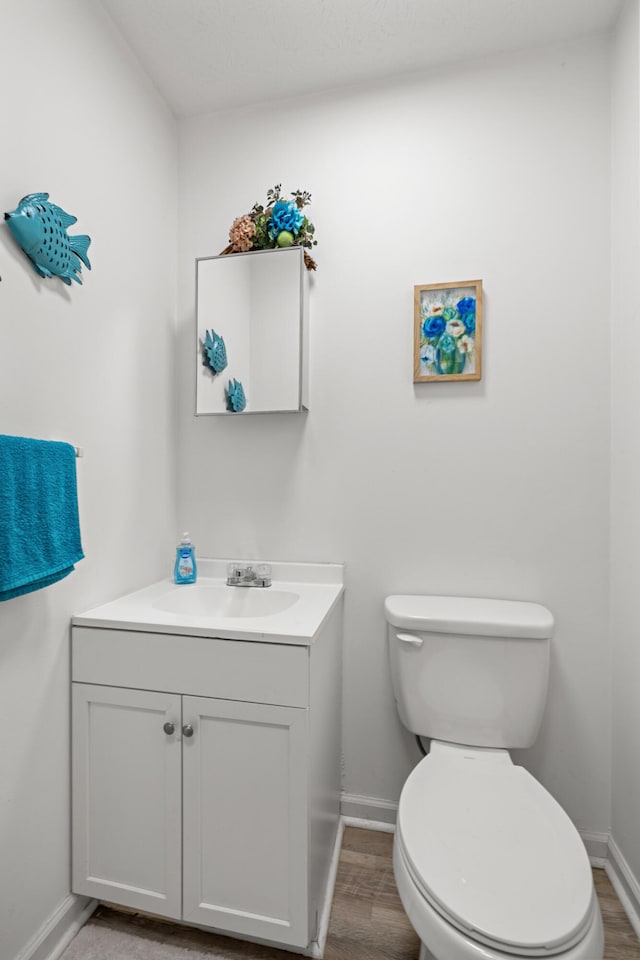 bathroom with wood-type flooring, vanity, and toilet