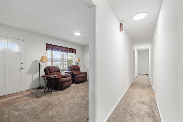 hall featuring a textured ceiling and light colored carpet