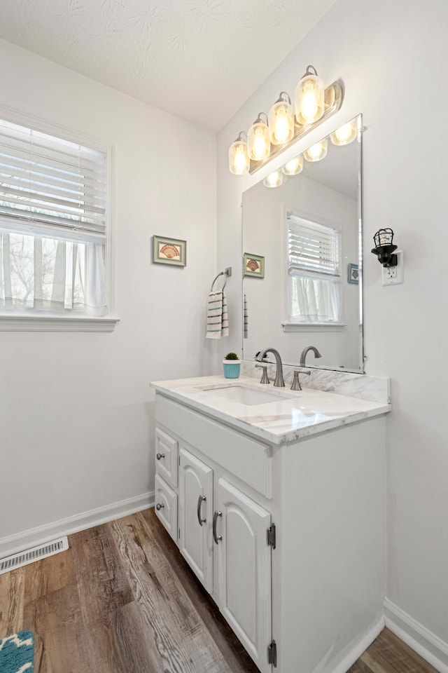 bathroom with vanity, wood-type flooring, and a textured ceiling