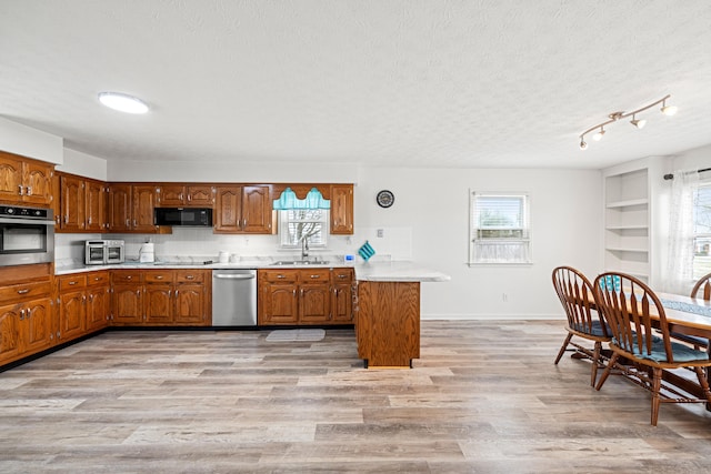 kitchen with a textured ceiling, a healthy amount of sunlight, black appliances, and light hardwood / wood-style floors