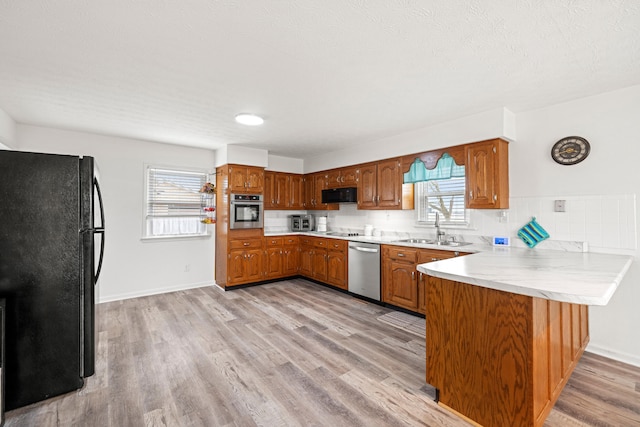 kitchen with light hardwood / wood-style flooring, sink, a wealth of natural light, black appliances, and kitchen peninsula