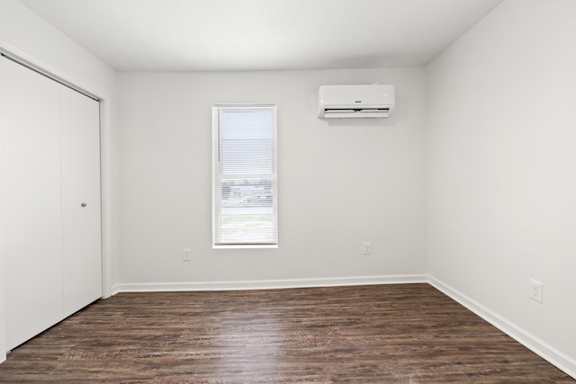 unfurnished bedroom featuring a closet, a wall mounted AC, and dark hardwood / wood-style floors