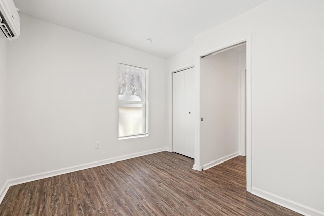 unfurnished bedroom featuring dark hardwood / wood-style flooring, an AC wall unit, and a closet