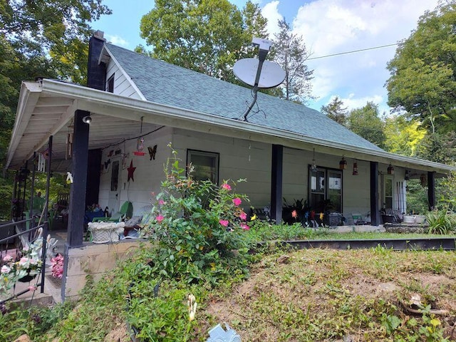 rear view of house featuring roof with shingles and a chimney