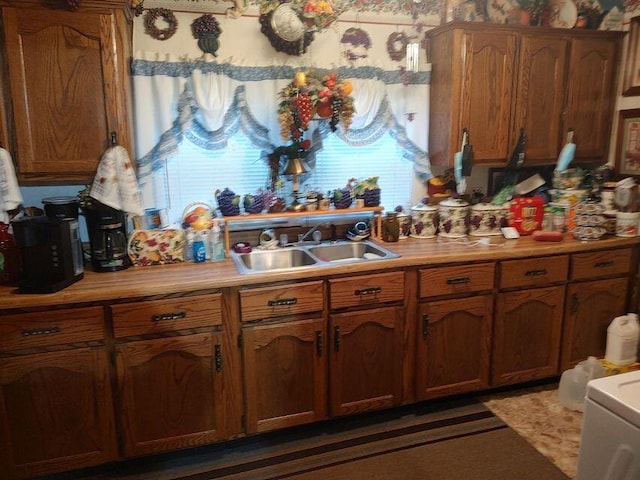 kitchen featuring brown cabinetry, light countertops, and a sink