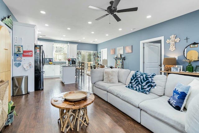 living room featuring sink, dark wood-type flooring, and ceiling fan