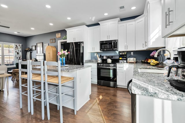 kitchen featuring white cabinets, stainless steel appliances, a kitchen island, and sink