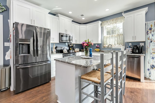 kitchen featuring appliances with stainless steel finishes, white cabinetry, a kitchen island, and a breakfast bar area