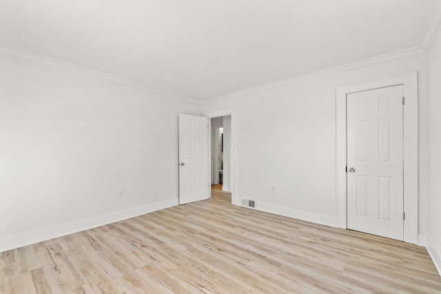 empty room featuring light wood-type flooring and ornamental molding